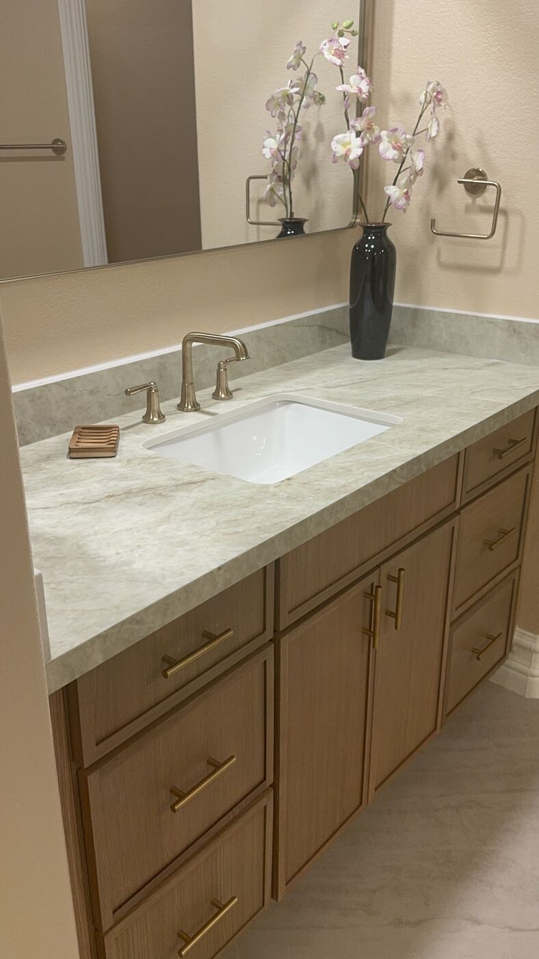 Bathroom vanity remodel with marble countertop and brushed gold faucet