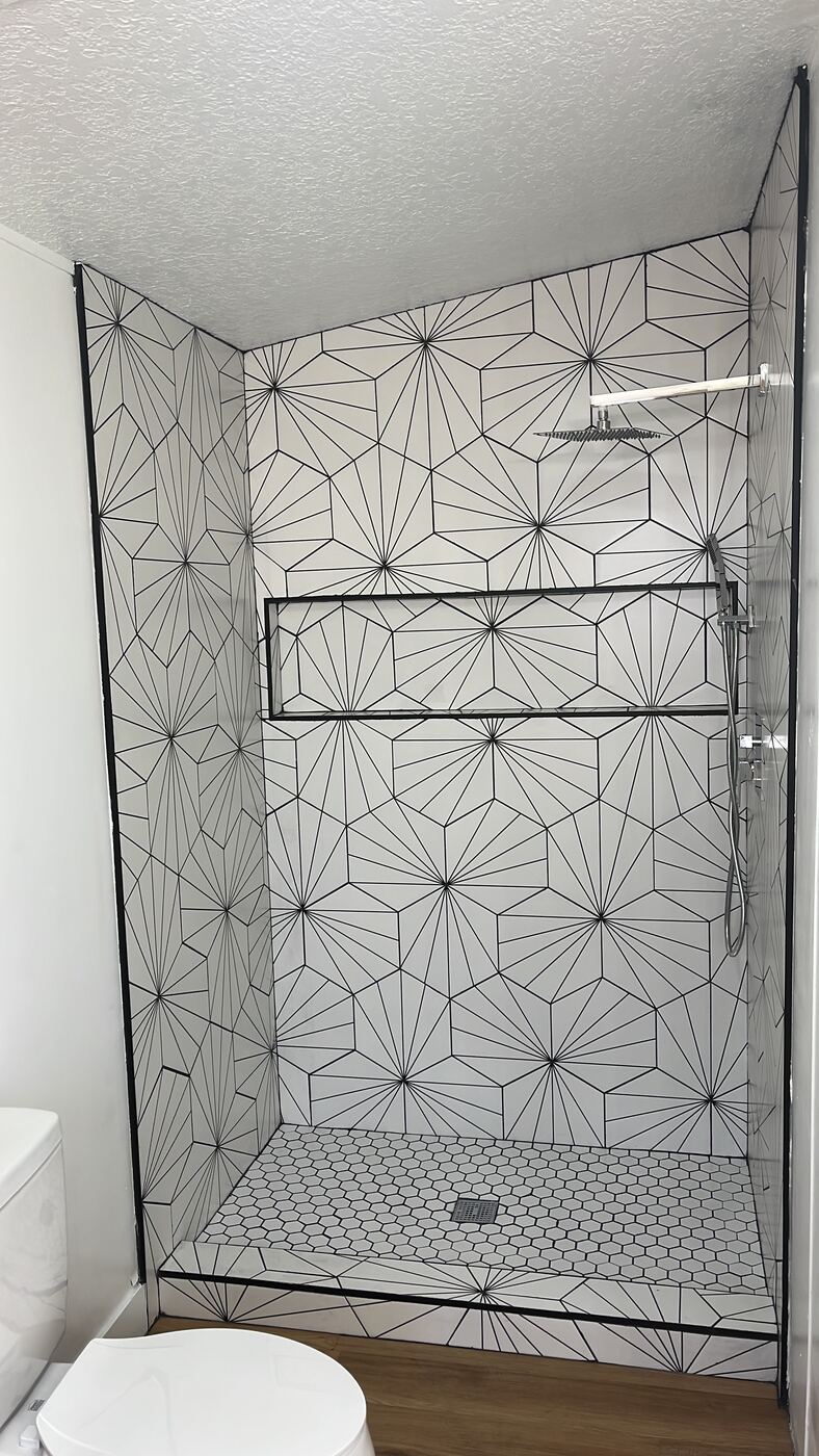 Walk-in shower with geometric starburst tile pattern and matte black hardware