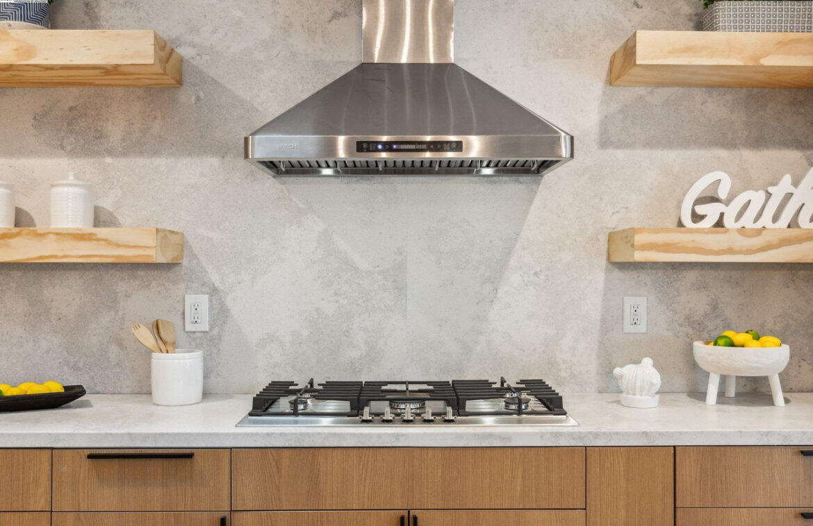 Detail shot of a concrete-look backsplash and stainless range hood