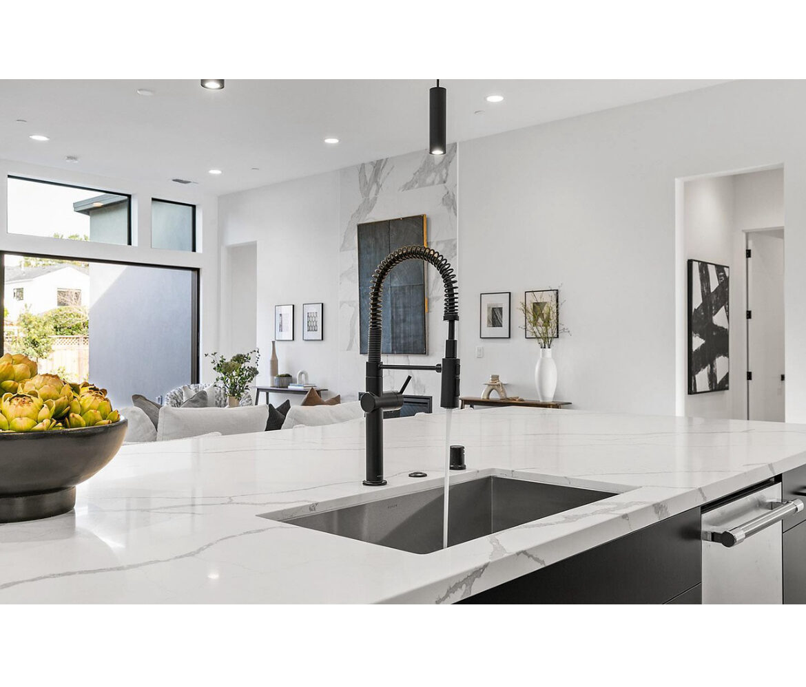 Detail shot of a matte black pull-down faucet over a quartz island